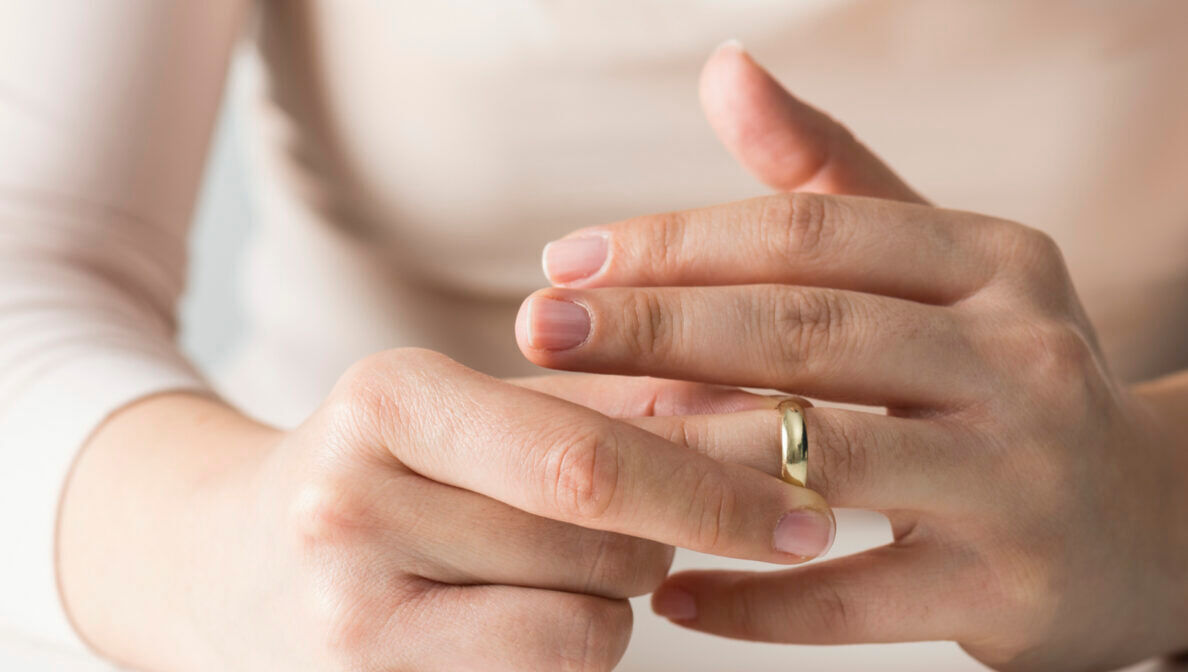 Nahaufnahme von zwei Händen, von denen die eine Hand am Ehering an der anderen Hand dreht.