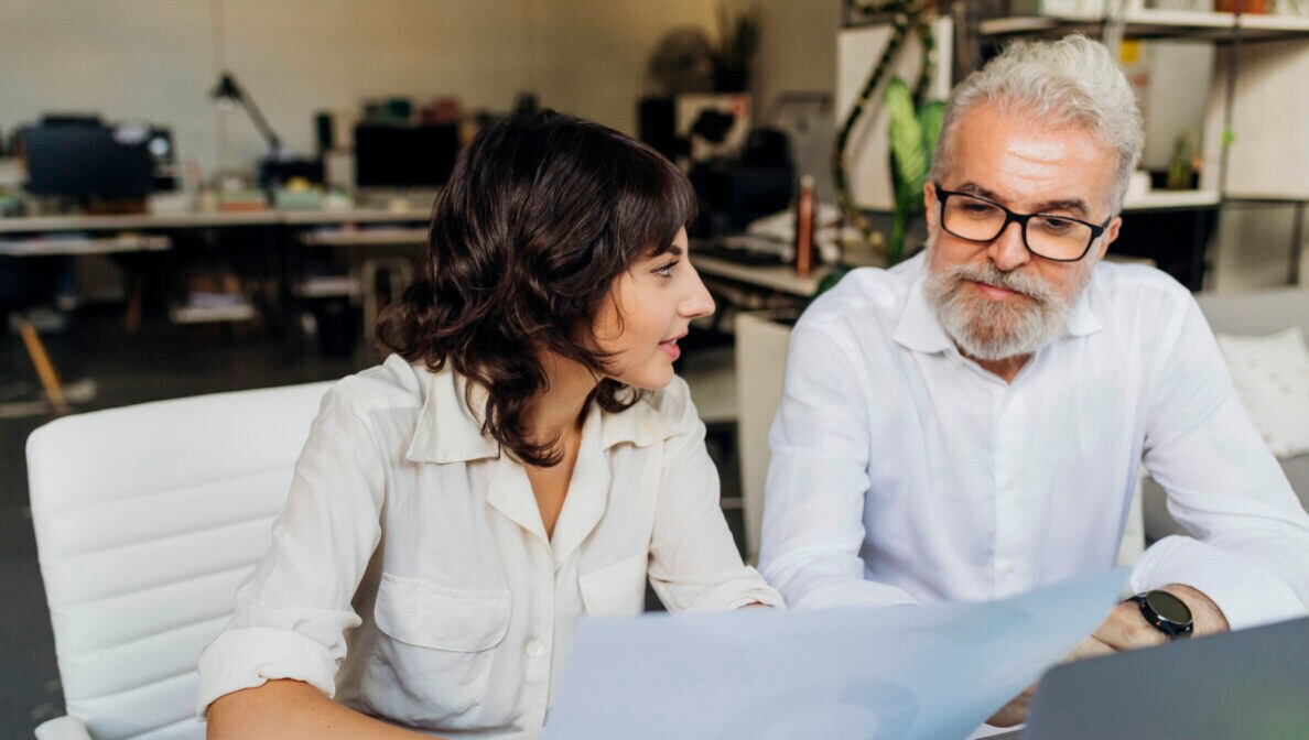 Zwei Personen schauen sich am Schreibtisch ein Diagramm an.