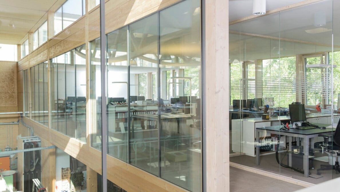 Büroräume mit Glaswänden auf einer höheren Etage über einer Werkstatt.
