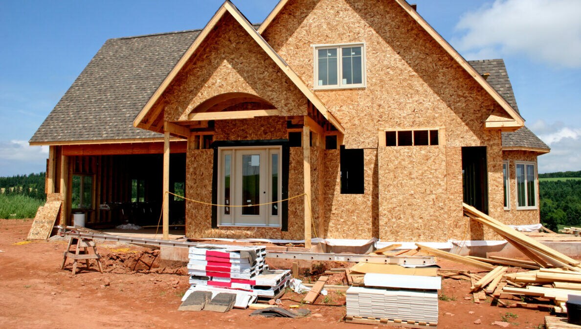 Ein im Bau befindliches Fertighaus, bei dem Wände und Dach bereits fertig sind.