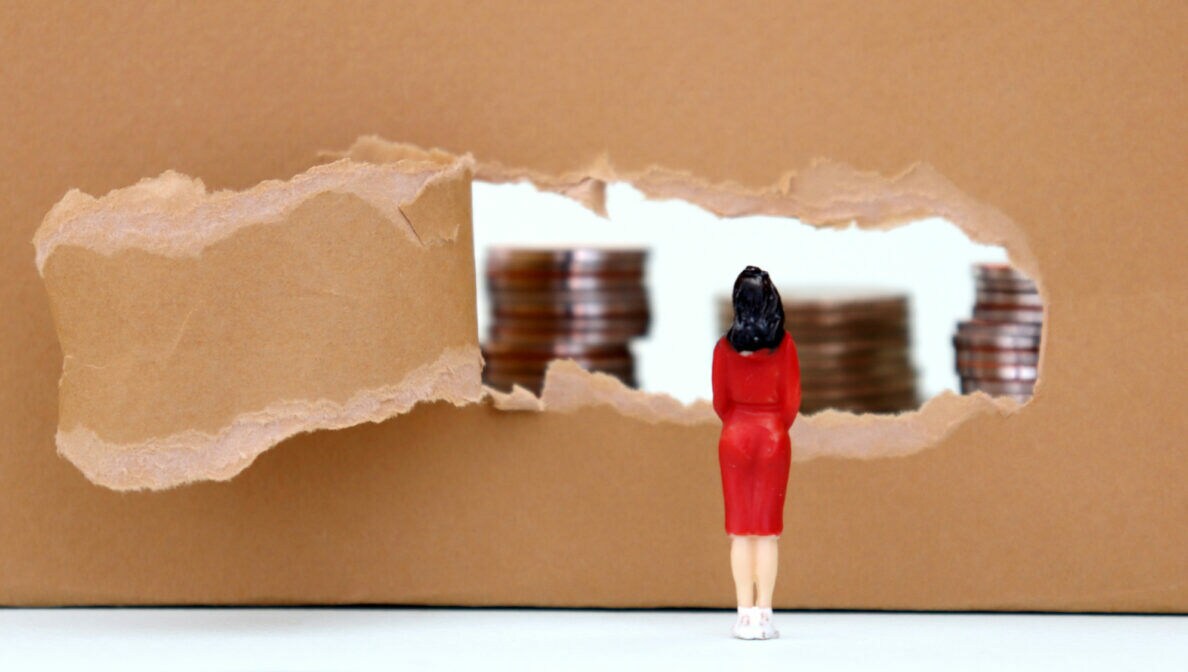 Eine Miniatur einer Frau vor einem aufgerissenen Stück Karton, hinter dem sich mehrere Stapel Münzen befinden.