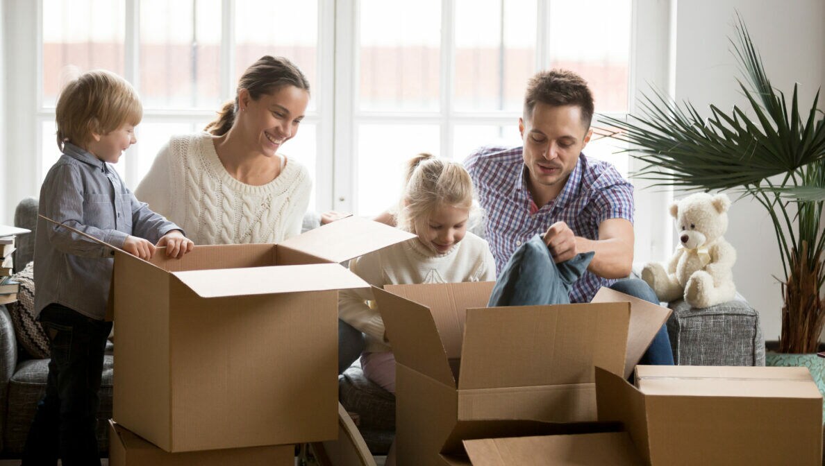 Ein Mann und eine Frau packen mit zwei Kindern Umzugskartons ein oder aus.