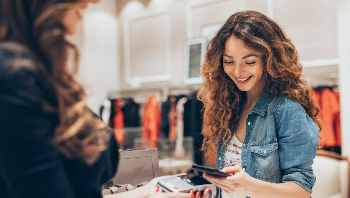 Eine Person bezahlt mit ihrem Smartphone in einem Bekleidungsgeschäft.