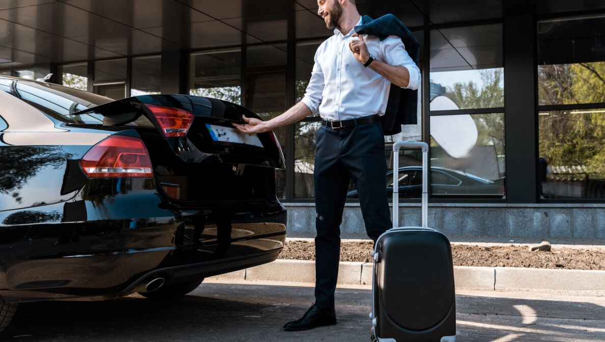 Bild: Perosn mit Koffer öffnet Kofferraum