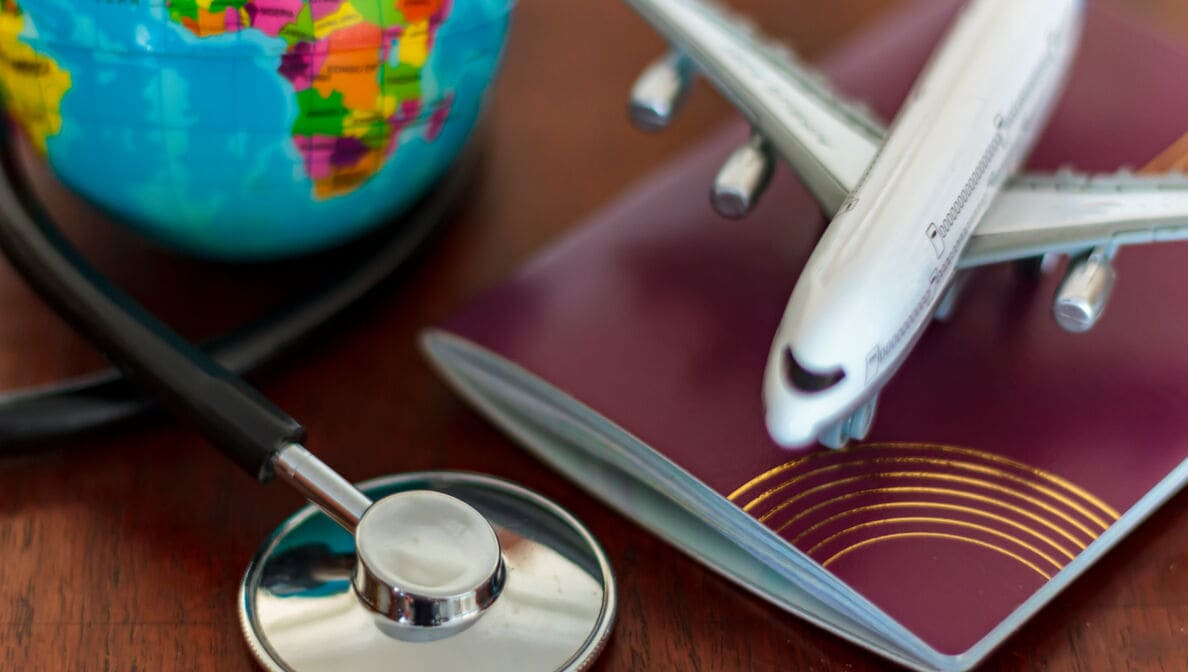Global Healthcare and travel insurance concept. Passport Stethoscope, airplane and globe on wooden table