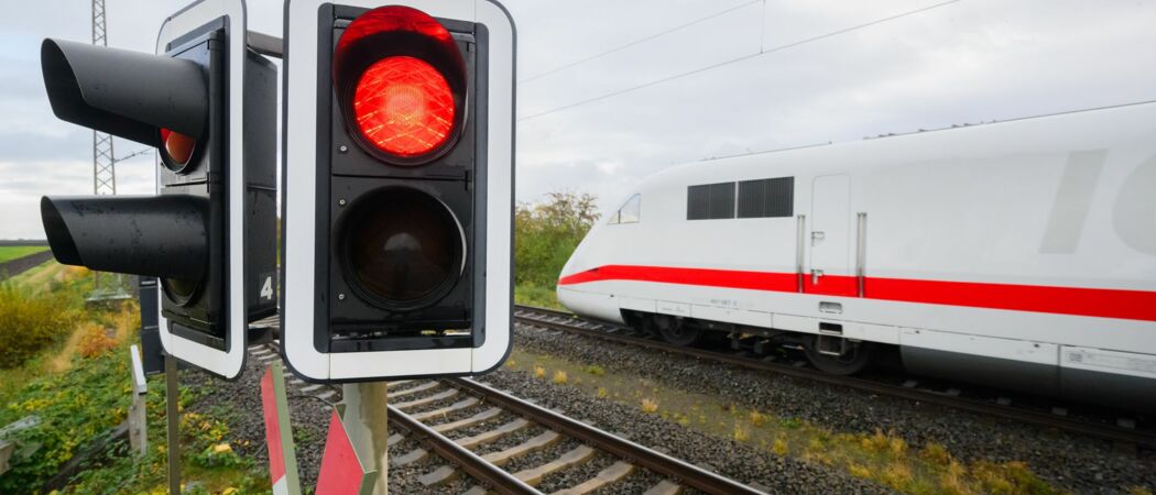 Eine rote Ampel leuchtet an einem Bahnübergang, ein ICE der Deutschen Bahn fährt vorbei. Die Strecke zwischen Mannheim und Stuttgart wird ab dem 17. April gesperrt. (zu dpa: «Bahnstrecke Mannheim-Stuttgart von Ostern an gesperrt»)