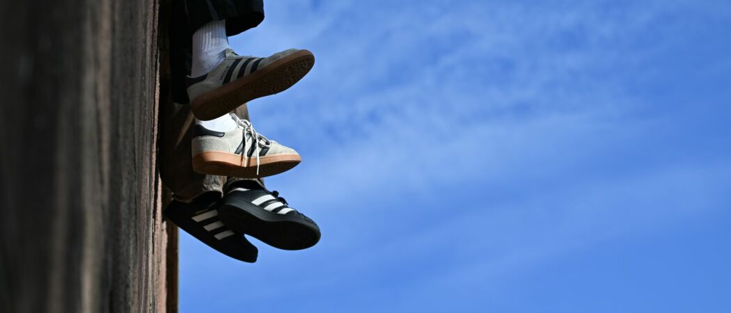 Ein junges Pärchen sitzt bei mildem, sonnigen Herbstwetter und blauem Himmel auf einer Mauer am Mainkai und lässt die Beine baumeln. (zu dpa: «Sneaker hoch im Kurs - Kein Ende des Booms in Sicht»)