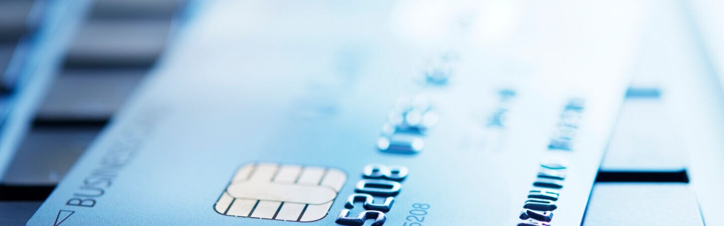 Blau getöntes Foto einer Kreditkarte, die auf der Tastatur eines Laptops liegt und deren Kreditkartennummer erkennbar ist.