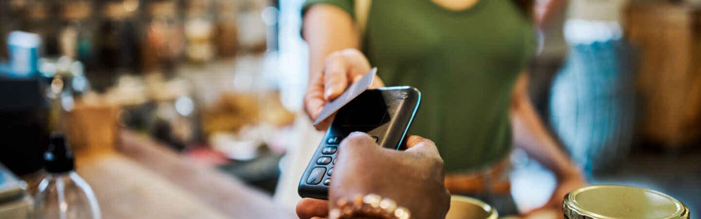 Eine Frau hält in einem Einkaufladen eine Karte an ein Kartenlesegerät