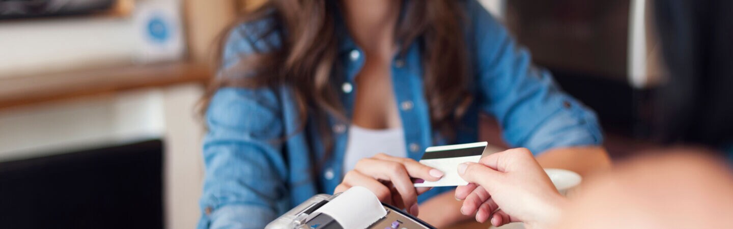 Eine Person zahlt mit einer Bankkarte an einem portablen Kartenlesegerät.