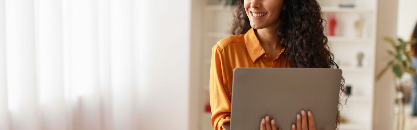Eine Person lehnt an einem runden Tisch und hält ein geöffnetes Notebook in den Händen.