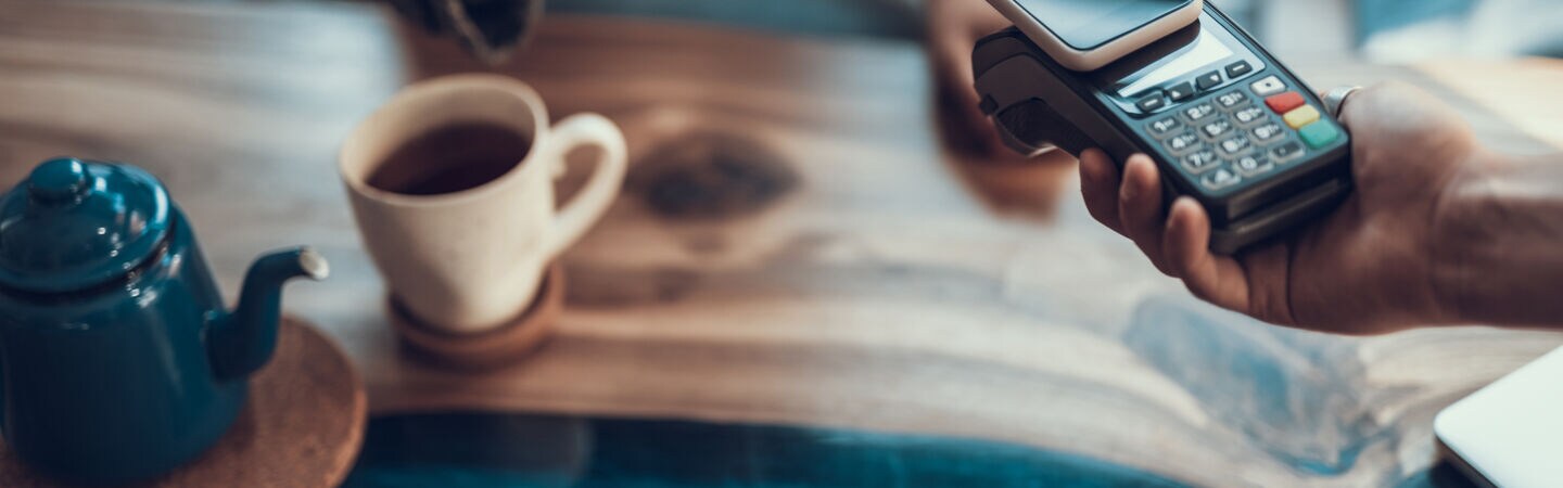 Nahaufnahme einer Hand, die mit einem Smartphone bezahlt.