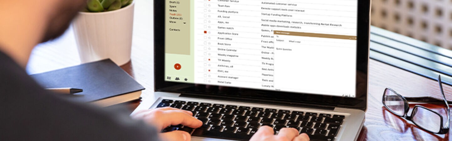 Mann tippt auf seinen Laptop.