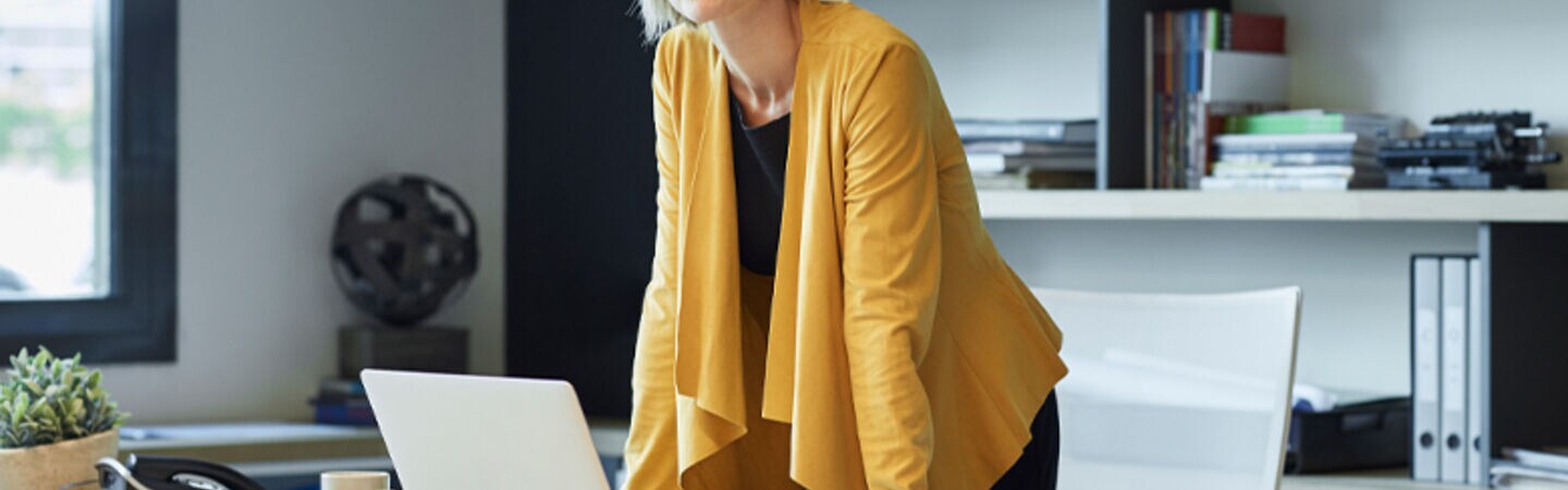 Eine Frau steht an ihren Schreibtisch.