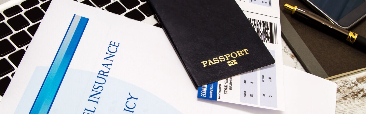 Blid: Reisepass Versicherungsvertrag auf Laptop liegend