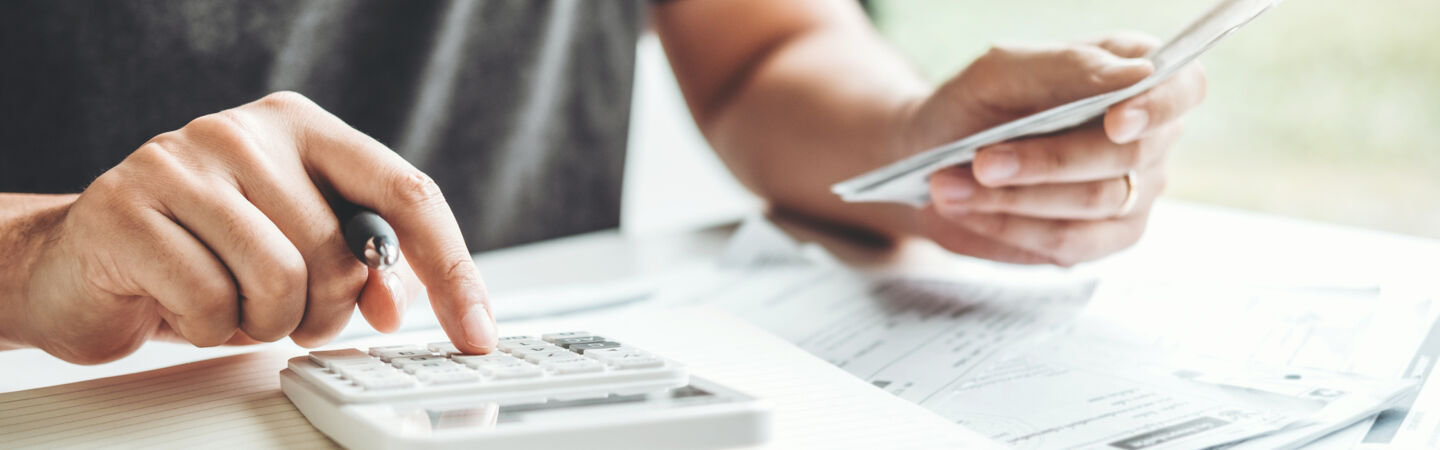 Artikelbild Person nutzt Taschenrechner und hat Dokumente vorliegen