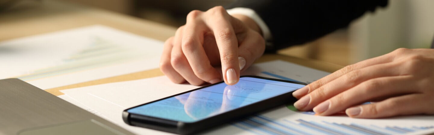Artikelbild Person klickt am Smartphone am Schreibtisch