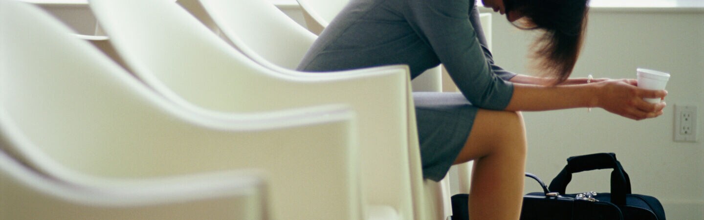 Frau wartet beim Flughafen mit gesenktem Kopf