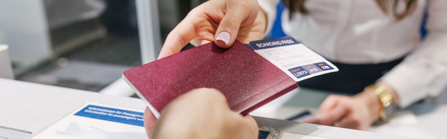 Person übergibt Fluggast ihren Reisepass wieder am Flughafenschalter