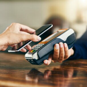 Ein Smartphone wird zum Bezahlen vor ein Ablesegerät gehalten