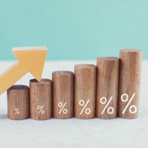 Darstellung einer Rendite von Geldanlagen durch Holzsäulen und einem nach rechts oben gerichteten Pfeil.