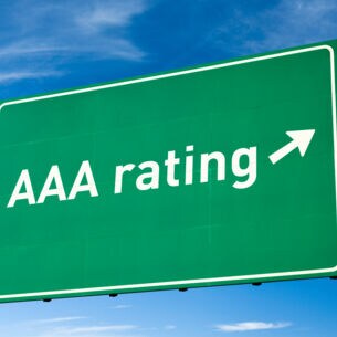 Ein grünes Verkehrsschild vor blauem Himmel mit der Aufschrift “AAA Rating” und einem Pfeil.