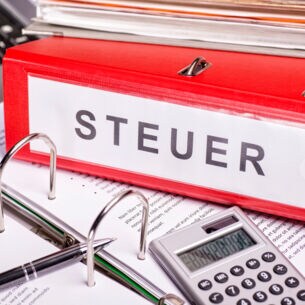 Taschenrechner, Papiere, eine Tastatur und Aktenordner mit der Aufschrift Steuer