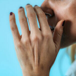 ine Hand, die in Flüstergeste vors Gesicht gehalten wird