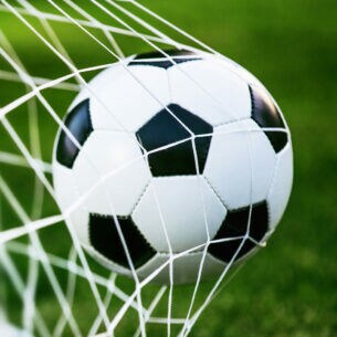 Fußball, der mit Schwung ins Tornetz fliegt