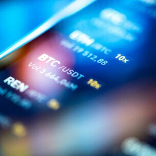 Detailaufnahme eines Displays mit Börsenabkürzungen von Kryptowährungen.