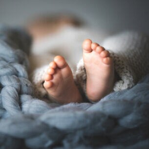 Füße eines Neugeborenes auf einer sehr grob gestrickten Decke