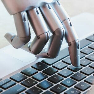 Eine Roboterhand, die auf einer Laptoptastatur tippt