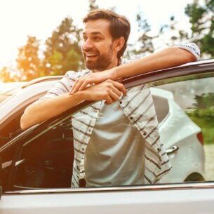 Ein Mann, der zwischen Auto und der geöffneten Wagentür steht