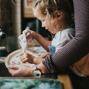 Ein kleines Kind wäscht zusammen mit einer Person ab