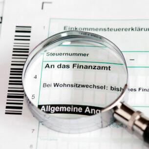 Eine Lupe, die auf einem Formular der Einkommenssteuererklärung liegt