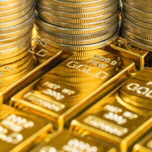 Drei Münzstapel stehen auf auf mehreren Goldbarren