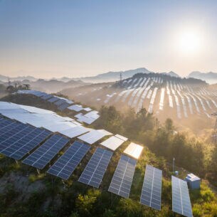 Blick von oben über grüne Hügel voller Solarpanels