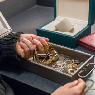 Nahaufnahme einer Person, die goldene Schmuckstücke aus einem Bankschließfach entnimmt