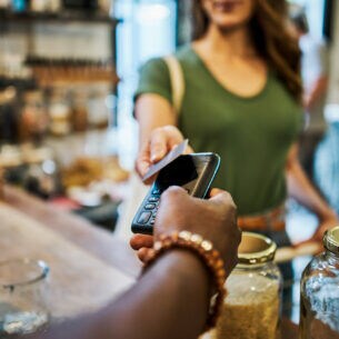 Eine Frau hält in einem Einkaufladen eine Karte an ein Kartenlesegerät