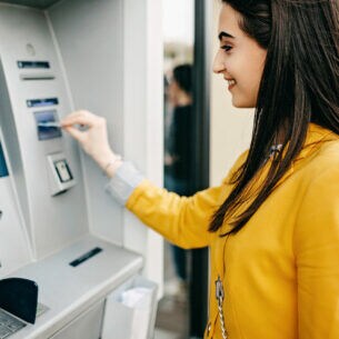 Eine Frau steckt eine Karte in den Eingabeschlitz eines Geldautomaten