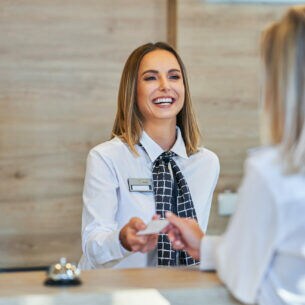 Eine Person an einer Rezeption nimmt von einer anderen Person eine Kreditkarte entgegen.