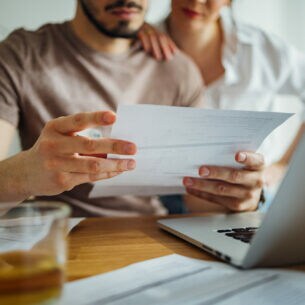 Zwei Personen sitzen am Tisch und prüfen eine Rechnung.
