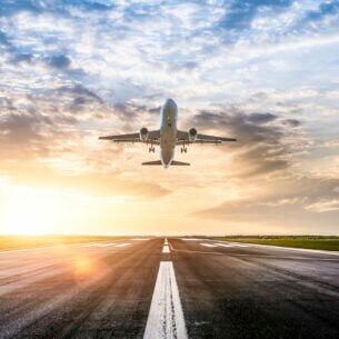 Ein Flugzeug startet bei Sonnenuntergang von der Landebahn.