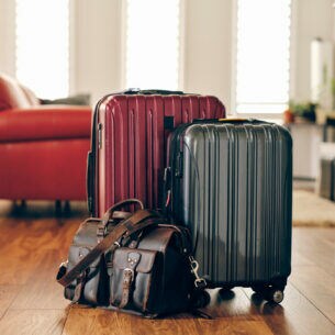 Zwei Koffer und eine Reisetasche stehen vor einem roten Sofa