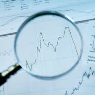 Blick auf Aktienkurse durch eine Lupe hindurch.