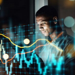 Eine Person blickt auf ein Laptop, über dem Bild liegt ein digitales Aktienchart.