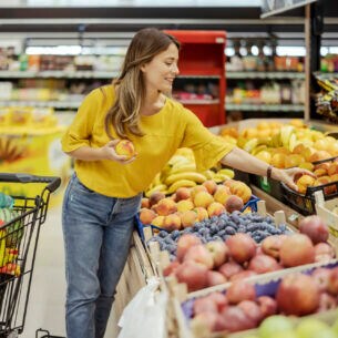 Eine Person greift im Supermarkt nach Pfirsichen.