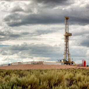 Fracking-Plattform auf einer kleinen Anhöhe, im Hintergrund sind Berge zu sehen