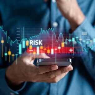 Eine Person hält ein Smartphone in der Hand, darüber ist die Visualisierung eines Aktienkurses zu sehen.