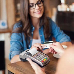 Eine Person zahlt mit einer Bankkarte an einem portablen Kartenlesegerät.